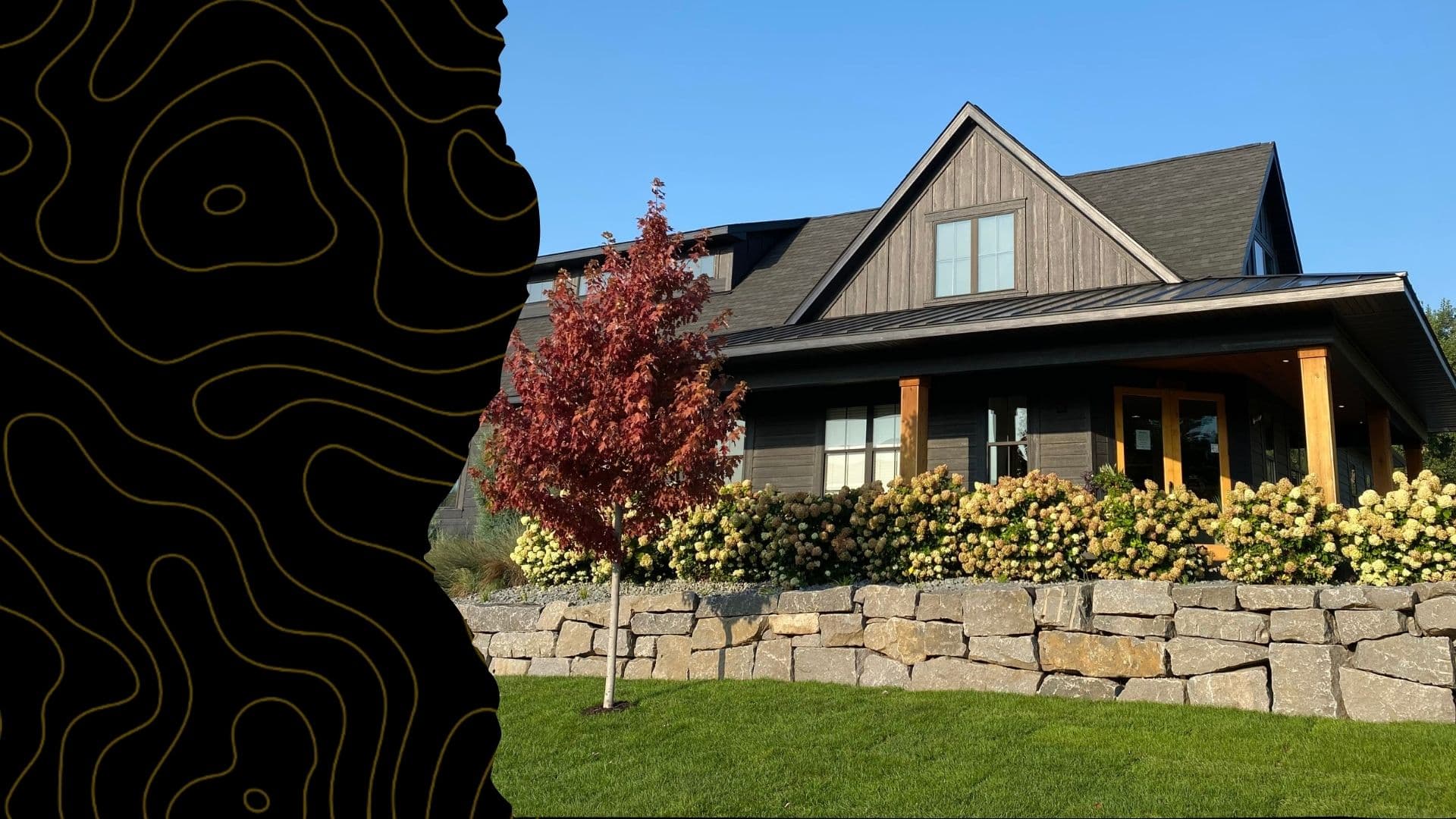 Finished boulder retaining wall and landscaping in front of a home