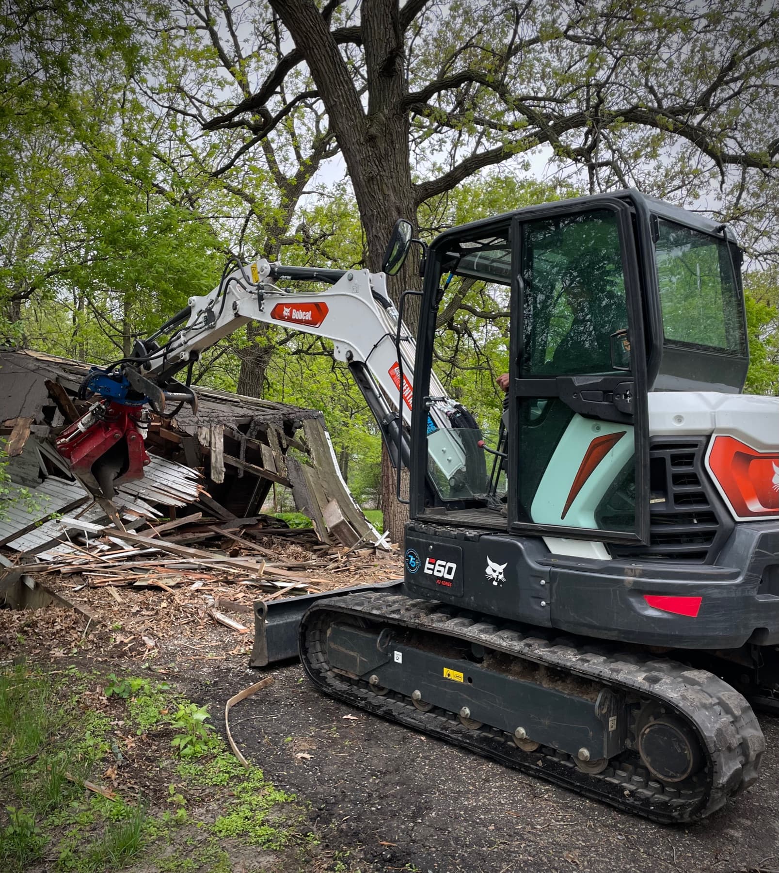 Compact excavator removing a small wood structure