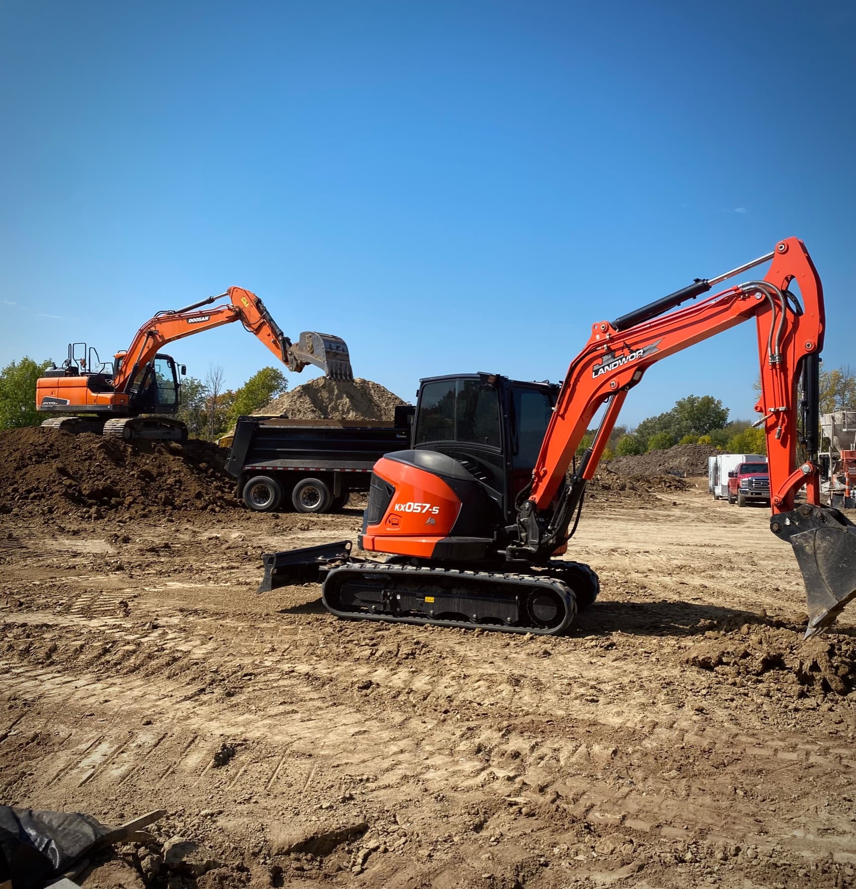Excavators and skid steer working on a graded building site
