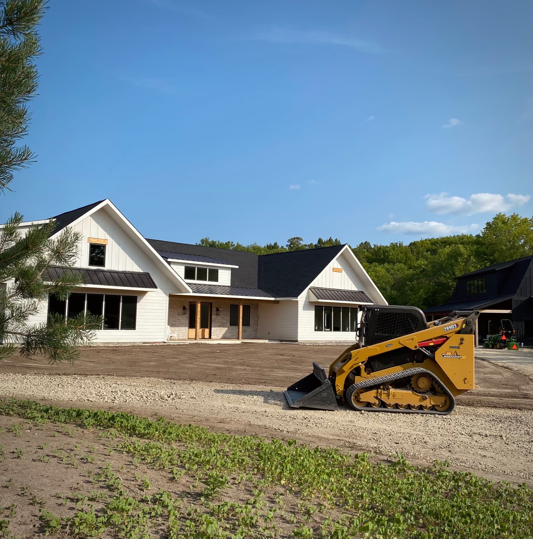 Track loader grading soil beside a newly built home